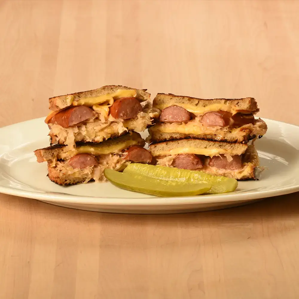 kielbasa and sauerkraut reuben sandwiches with pickles on it