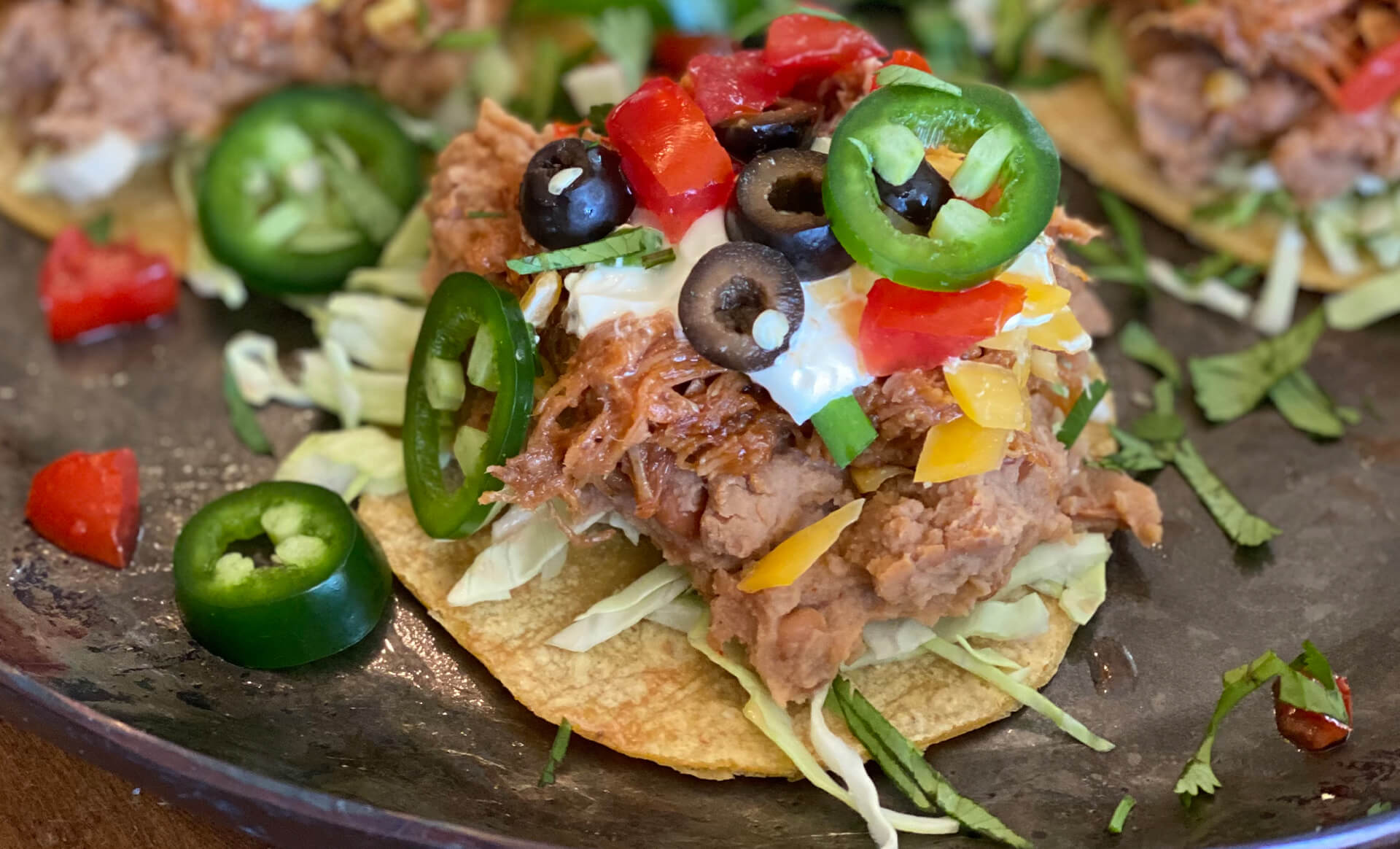 Seven layer tostada bites with pulled pork and jalapeno