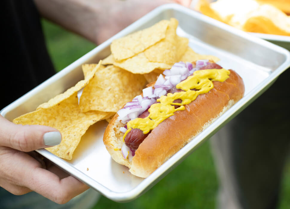 hands holding hot dog tray with sides