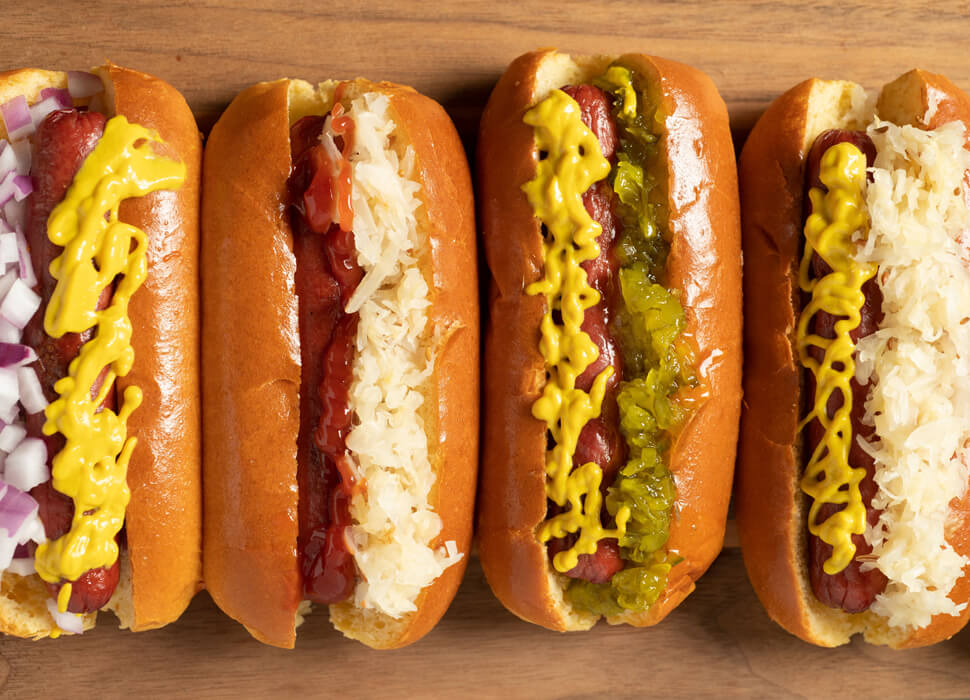 four hot dogs dressed and lined up