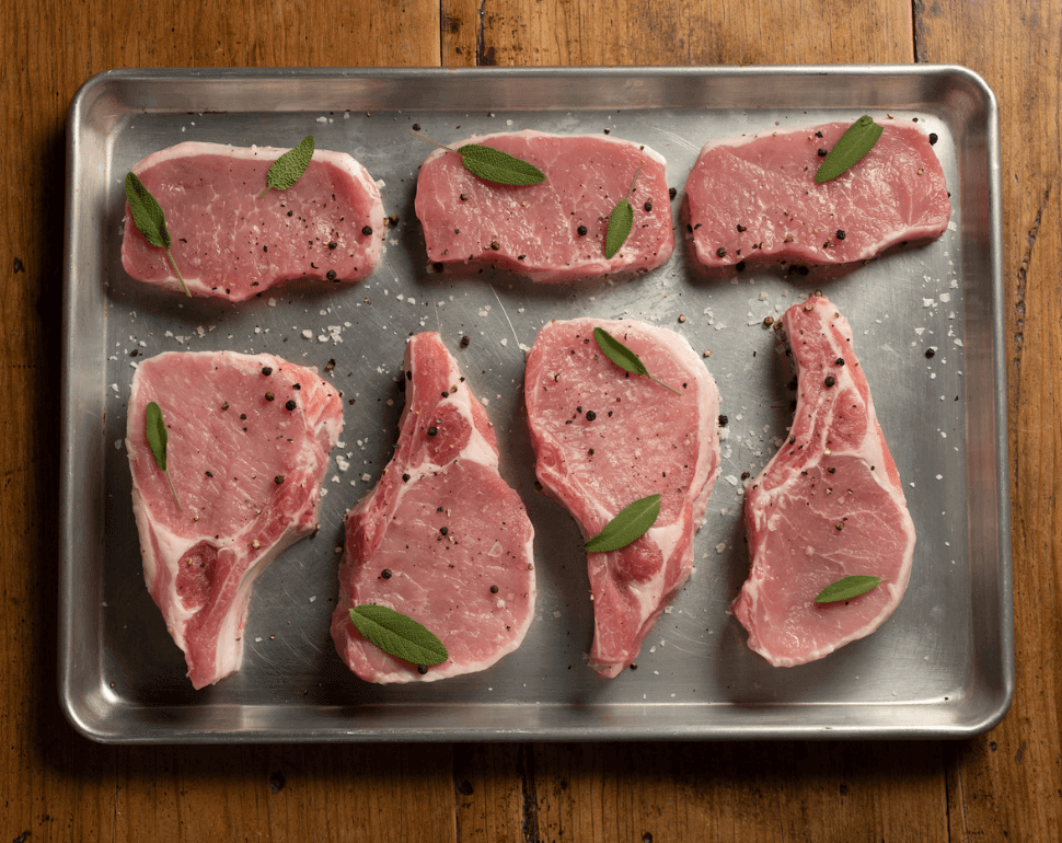 Raw pork chops on a metal pan