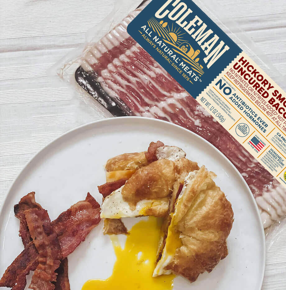 Bacon and croissant on a plate next to a package of bacon