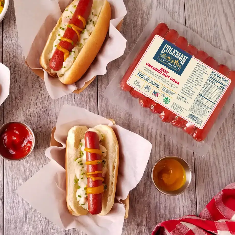 two dressed hot dogs with coleman hot dog packaging